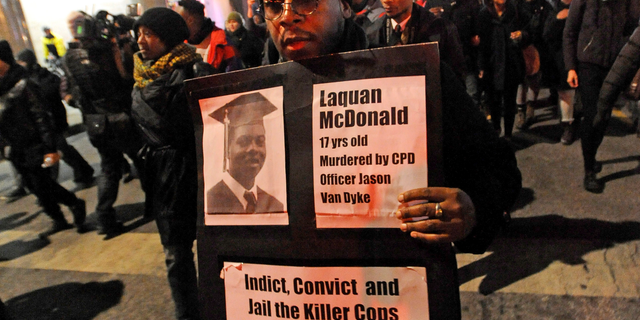 FILE - In this Nov. 24, 2015 file photo, a man holds a sign with a photo of Laquan McDonald on it, during a protest of the police shooting 17-year-old McDonald, in Chicago. The city of Chicago is watching closely for word of a verdict in the case of Chicago police Officer Jason Van Dyke charged with murder in the 2014 shooting of McDonald. The Chicago Police Department has canceled days off and put officers on 12-hour shifts. (AP Photo/Paul Beaty, File)