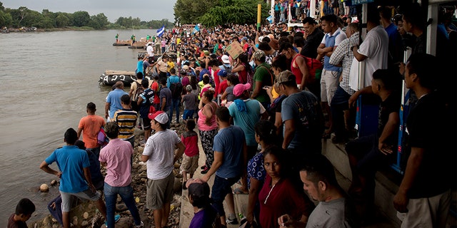 Hundreds of Honduran migrants stand at the shore of the Suchiate river on the border between Guatemala and Mexico, in Tecun Uman, Guatemala.
