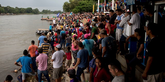 Hundreds of Honduran migrants stand at the shore of the Suchiate river on the border between Guatemala and Mexico, in Tecun Uman, Guatemala.