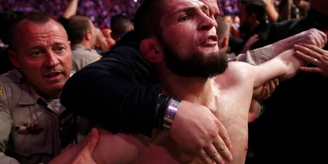Khabib Nurmagomedov is held back outside of the cage after fighting Conor McGregor in a lightweight title mixed martial arts bout at UFC 229 in Las Vegas on Oct. 6, 2018. (Associated Press)