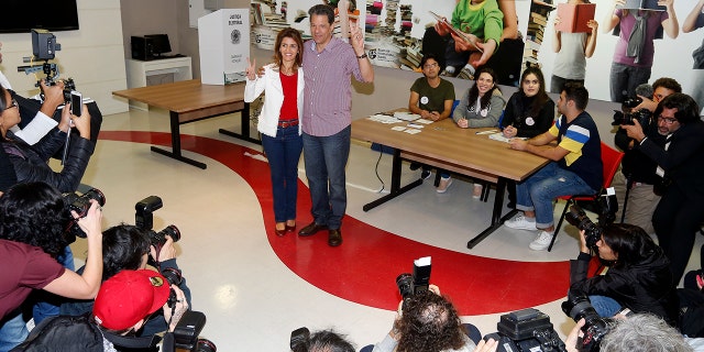 Brazil's presidential candidate for the Workers Party Fernando Haddad, accompanied by his wife Ana Estela Haddad, gestures after casting his ballot during general elections, in Sao Paulo, Brazil, Sunday, Oct. 7, 2018. (AP Photo/Andre Penner)