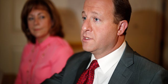 FILE - In this July 2, 2018, file photo, Democratic nominee for Colorado's gubernatorial seat, U.S. Rep. Jared Polis, talks during an interview as his choice for lieutenant governor running mate, Dianne Primavera, listens during a stop in their campaign headquarters in Denver. Polis will face Republican Walker Stapleton, who has served as the state's treasurer for the past eight years, for Colorado's governorship in the November election. (AP Photo/David Zalubowski, File)
