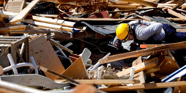 A member of a South Florida urban search and rescue team sifts through a debris pile for survivors of hurricane Michael in Mexico Beach, Fla., Sunday, Oct. 14, 2018.