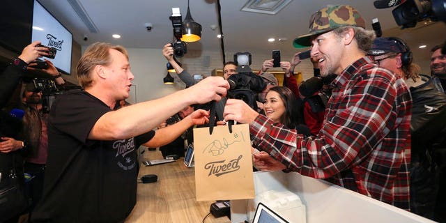 Canopy Growth CEO Bruce Linton, left to right, passes a bag with the first legal cannabis for recreation use sold in Canada to Nikki Rose and Ian Power at the Tweed shop on Water Street in St. John's N.L. at 12:01 am NDT on Wednesday Oct. 17, 2018