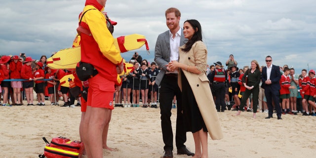 Britain's Prince Harry and Meghan, Duchess of Sussex talk to life guards at South Melbourne Beach in Melbourne, Australia, Thursday, Oct. 18, 2018. Prince Harry and his wife Meghan are on day two of their 16-day tour of Australia and the South Pacific. (Ian Vogler/Pool Photo via AP)