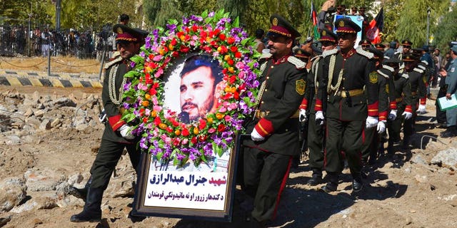 Guards of honor carry a photo of Gen. Abdul Raziq, Kandahar police chief, who was killed by a guard, during his burial ceremony in Kandahar, Afghanistan, Friday, Oct. 19, 2018.