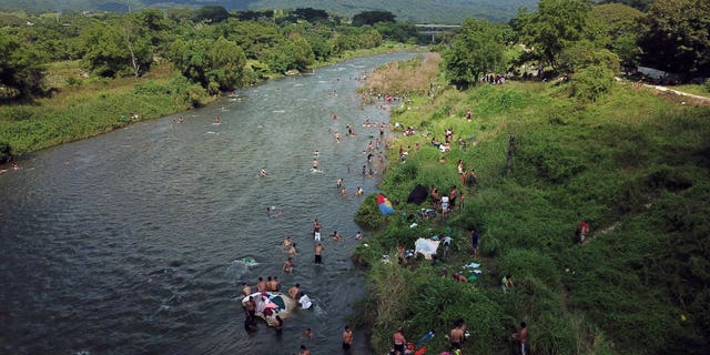 Honduran migrants take a bath in a river in Pijijiapan, Mexico, Thursday, Oct. 25, 2018. Thousands of Central American migrants renewed their hoped-for march to the United States on Wednesday, setting out before dawn with plans to travel another 45 miles (75 kilometers) of the more than 1,000 miles that still lie before them. (AP Photo/Rodrigo Abd)