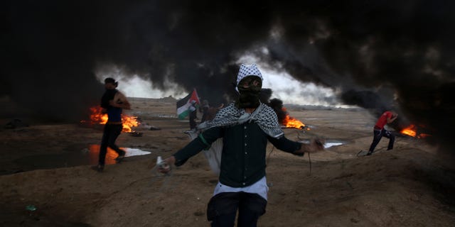 Protesters run when burn tires near the fence of the Gaza Strip border with Israel during a protest east of east of Gaza City, Friday, Oct. 26, 2018. (AP Photo/Adel Hana)