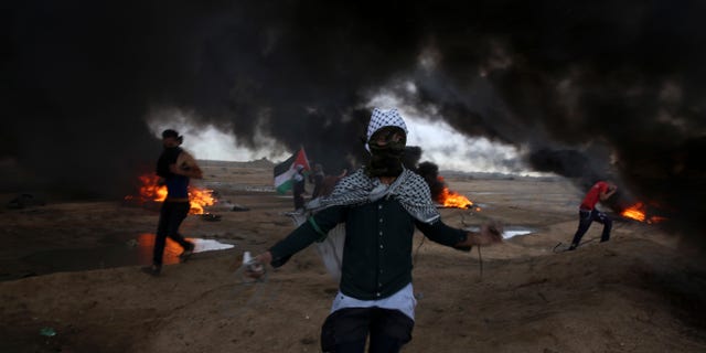 Protesters run when burn tires near the fence of the Gaza Strip border with Israel during a protest east of east of Gaza City, Friday, Oct. 26, 2018. (AP Photo/Adel Hana)