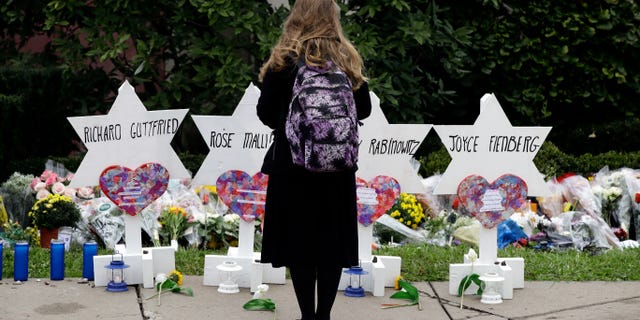 A person stands in front of Stars of David that are displayed in front of the Tree of Life Synagogue with the names of those killed in Saturday's deadly shooting in Pittsburgh, Monday, Oct. 29, 2018. (AP Photo/Matt Rourke)