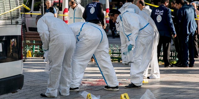 Tunisian forensic experts work on the scene of an attack after a 30-year-old woman blew herself on the Habib Bourguiba avenue in Tunis, Tunisia. (AP Photo/Riadh Dridi)