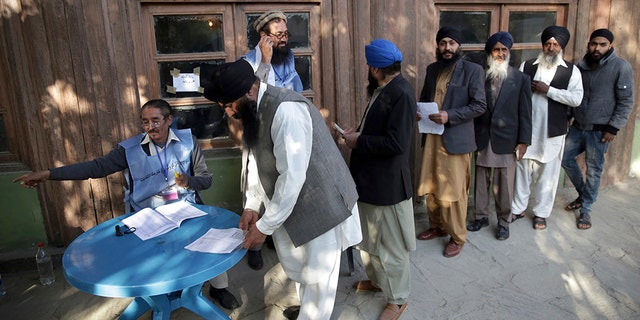 Voters from the minority Sikh register to cast ballots in parliamentary elections in  Kabul, Afghanistan, Saturday. Tens of thousands of Afghan forces fanned out across the country as voting began in the elections that followed a campaign marred by relentless violence. (AP Photo/Massoud Hossaini)