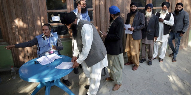 Voters from the minority Sikh register to cast ballots in parliamentary elections in Kabul, Afghanistan, Saturday. Tens of thousands of Afghan forces fanned out across the country as voting began in the elections that followed a campaign marred by relentless violence. (AP Photo/Massoud Hossaini)