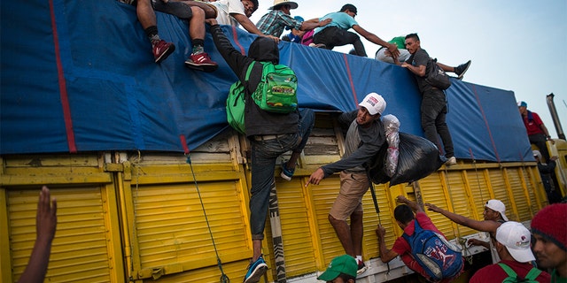 Migrants climbing on a truck to ride on the road that connects Tatanatepec with Niltepec, Mexico. (AP Photo/Rodrigo Abd)