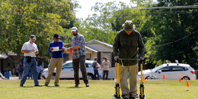 FILE - In this Thursday, May 17, 2018 file photo, Tulane University researcher Dr. Ryan Gallacher uses ground penetrating radar equipment with a team from Tulane, on a piece of land that may hold a mass grave from a Reconstruction-era racial massacre in Thibodaux, La. A suspected burial ground where the bodies of an 1887 racial massacre may have been dumped should be studied further, a scientific team suggests, Wednesday, Oct. 24, 2018. (AP Photo/Gerald Herbert, File)