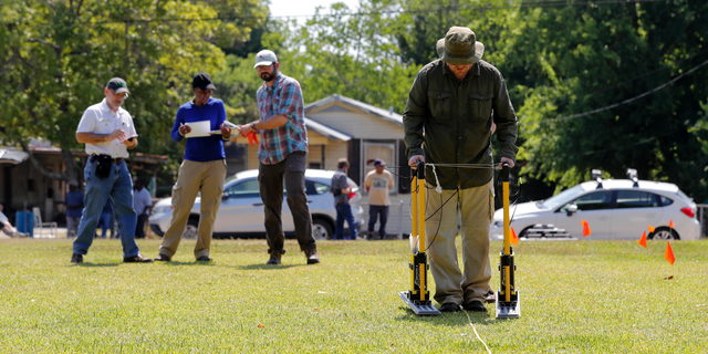 FILE - In this Thursday, May 17, 2018 file photo, Tulane University researcher Dr. Ryan Gallacher uses ground penetrating radar equipment with a team from Tulane, on a piece of land that may hold a mass grave from a Reconstruction-era racial massacre in Thibodaux, La. A suspected burial ground where the bodies of an 1887 racial massacre may have been dumped should be studied further, a scientific team suggests, Wednesday, Oct. 24, 2018. (AP Photo/Gerald Herbert, File)