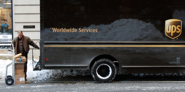 FILE- In this Jan. 5, 2018, photo, a UPS delivery driver loads his cart with packages from his truck, in Boston. UPS Inc. reports earnings Wednesday, Oct. 24. (AP Photo/Bill Sikes, File)