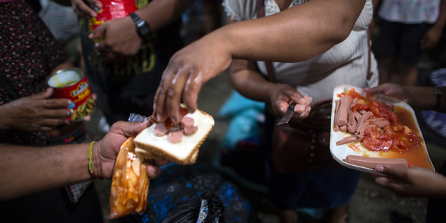 Central American migrants traveling with a caravan to the U.S. receive donated food outside the Catholic Church in Mapastepec, Mexico, Wednesday, Oct. 24, 2018. Thousands of Central American migrants renewed their hoped-for march to the United States on Wednesday, setting out before dawn with plans to travel another 45 miles (75 kilometers) of the more than 1,000 miles that still lie before them. (AP Photo/Rodrigo Abd)