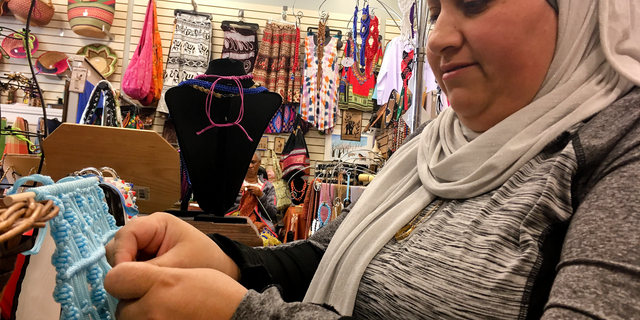 Former Iraqi refugee Nadeen Yousef creates hand crafts to sell at the West Side Bazaar, where refugees sell clothes, crafts and food, on Friday, Sept. 28, 2018, in Buffalo, N.Y. Thousands of refugees have settled in Buffalo in recent years even as others have left the city. Some locals worry that the Trump administration's policies reducing the numbers of new arrivals will harm the city's economy. (AP Photo/ Michael Hill)