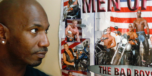 Former male dancer David Crosby, left, looks at a poster showing Cesar Sayoc, second from bottom and at right on motorcycle next to Crosby, Saturday, Oct. 27, 2018, in Hopkins, Minn. Sayoc was identified by authorities as the Florida man who allegedly sent pipe bombs to some of President Donald Trump's most prominent critics. Crosby said he worked with Sayoc about 12 years ago. (AP Photo/Jim Mone)