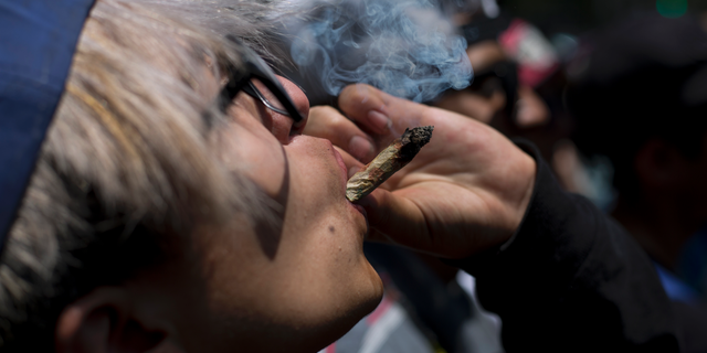 FILE - In this April 20, 2018 file photo, a young man smokes marijuana to celebrate the International Day for Cannabis in Mexico City. Mexico’s Supreme Court issued two more rulings Wednesday, Oct. 31, ordering that complainants in individual cases be allowed to use marijuana for recreational purposes, establishing a precedent which will apply for others that a blanket prohibition is unconstitutional. (AP Photo/Eduardo Verdugo, File)
