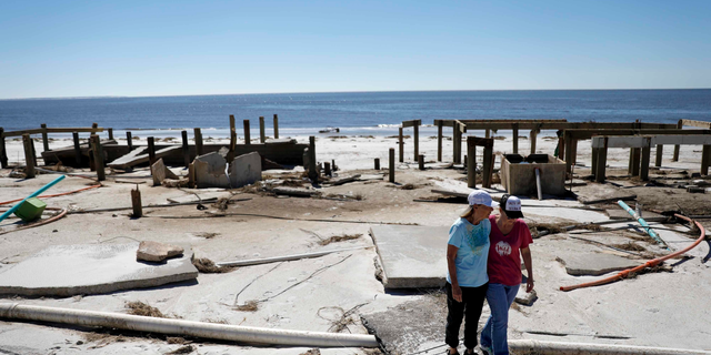 FILE - In this Oct. 12, 2018, file photo, Joy Hutchinson, left, is comforted by her daughter Jessica Hutchinson, as she returns to find her home swept away from hurricane Michael in Mexico Beach, Fla. The tropical weather that turned into monster Hurricane Michael began as a relatively humble storm before rapidly blossoming into the most powerful cyclone ever to hit the Florida Panhandle, causing wrenching scenes of widespread destruction.(AP Photo/David Goldman, File)
