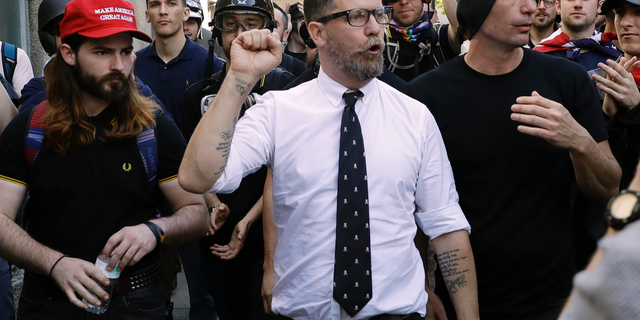 FILE - In this April 27, 2017 file photo, Gavin McInnes, center, founder of the far-right group Proud Boys, is surrounded by supporters after speaking at a rally in Berkeley, Calif. McInnes and his Proud Boys group have been banned from Facebook and Instagram because of policies prohibiting hate groups.(AP Photo/Marcio Jose Sanchez, File)