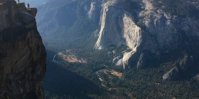 FILE - In this Sept. 27, 2018 file photo a wedding couple are seen being photographed at Taft Point in California's Yosemite National Park. A Yosemite National Park official says two visitors have died in a fall from the popular overlook. Park rangers are trying to recover the bodies of a man and a woman Thursday, Oct.25, 2018. He didn't say when the couple fell from Taft Point. Gediman says the deaths are being investigated and offered no other information. (AP Photo/Amanda Lee Myers, File)