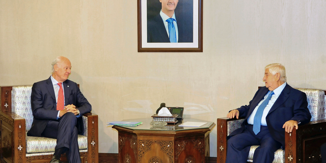 In this photo released by the Syrian official news agency SANA, Syria's Foreign Minister Walid al-Moallem, right, meets with U.N. Special Envoy for Syria Staffan de Mistura, in Damascus, Syria, Wednesday, Oct. 24, 2018. Syrian state media said al-Moallem has told the U.N. envoy that the constitution is a "sovereign" matter and Damascus will not allow any foreign intervention regarding it. (SANA via AP)