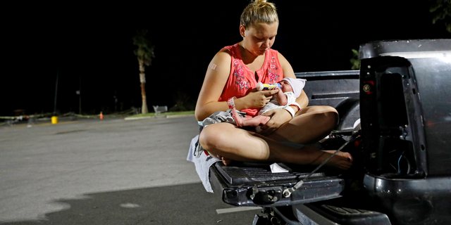 Lorrainda Smith, feeds her two-day-old son Luke out of the back of her pickup truck while preparing to spend the first night out of the hospital with her newborn and husband Wilmer Capps in a parking lot in Panama City, Fla., Monday, Oct. 15, 2018, as their home was badly damaged from Hurricane Michael. "One day we had it all, the next we had nothing," added Smith. "This is not what I thought I'd be bringing him back to." (AP Photo/David Goldman)