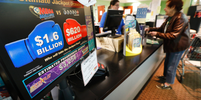 A customer buys a Mega Millions lottery ticket at a local grocery store, Tuesday, Oct. 23, 2018, in Des Moines, Iowa. Lottery players will have a chance at winning an estimated $1.6 billion jackpot in Tuesday night's Mega Millions drawing. (AP Photo/Charlie Neibergall)