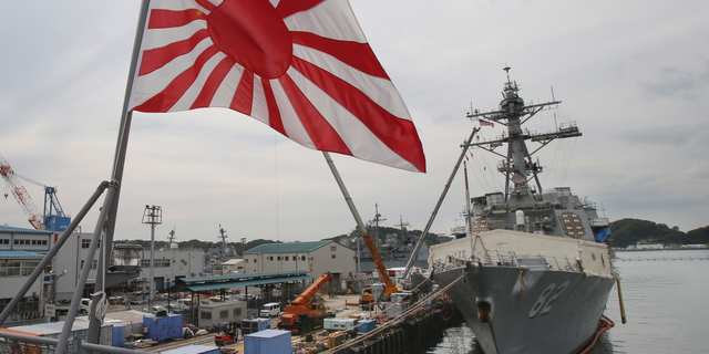 Japan's military flag, Risi ng Sun Flag, flutters on Japan's Maritime Self-Defense Force tanker JS Kunisaki anchored in Yokosuka, near Tokyo, in this May 27, 2014, file photo.