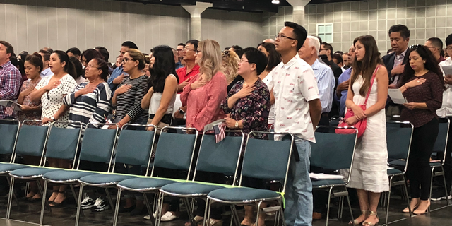 In this Sept. 18, 2018 photo new American citizens stand during a naturalization ceremony in Los Angeles. More than 700,000 immigrants are waiting on their applications to become U.S. citizens, a process that in many parts of the country now takes a year or more. The number of aspiring Americans surged during 2016, jumping 27 percent from a year ago as Donald Trump made cracking down on immigration a central point of his presidential campaign. (AP Photo/Amy Taxin)