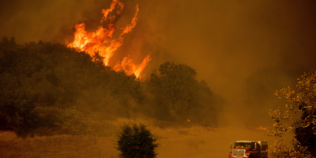 FILE - In this Dec. 9, 2017 file photo, a fire engine passes flames as a wildfire burns along Santa Ana Road near Ventura, Calif. Southern California Edison said Tuesday, Oct. 30, 2018, its equipment likely sparked one of two ignition points for Thomas fire, a wildfire that tore through California's central coast last year. (AP Photo/Noah Berge, File)