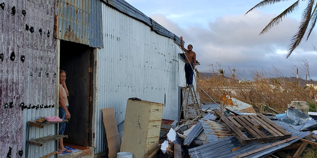This photo released by Edwin Propst shows a man repairing damage to a home from Super Typhoon Yutu in Saipan, an island of the Northern Mariana Islands, Monday, Oct. 29, 2018. Elections are being postponed by a week in a Pacific U.S. territory still without electricity after a super typhoon destroyed homes, toppled trees, utility poles and left a woman dead. (Edwin Propst via AP)