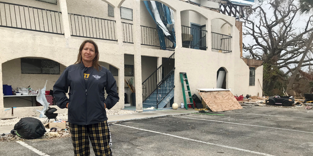 This Oct. 23, 2018 photo shows Regina Ferrell, a fourth grade teacher in Panama City, standing in front of her damaged condo building in Panama City, Fla. Since Hurricane Michael swept through the area, many teachers like Ferrell are sleeping in half-destroyed homes, living in cars or staying in their classrooms. (AP Photo/Tamara Lush)