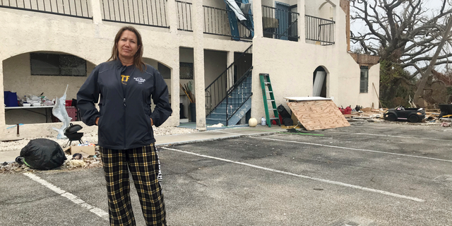This Oct. 23, 2018 photo shows Regina Ferrell, a fourth grade teacher in Panama City, standing in front of her damaged condo building in Panama City, Fla. Since Hurricane Michael swept through the area, many teachers like Ferrell are sleeping in half-destroyed homes, living in cars or staying in their classrooms. (AP Photo/Tamara Lush)