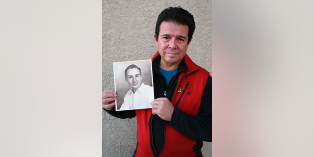 This Tuesday, Oct. 30, 2018, photo provided by Reuben Ortiz, shows Reuben Ortiz holding a photo of the Rev. Jerome Coyle in Albuquerque, N.M. Ortiz says he was angered to learn that Coyle, who had been living at his home until recently, admitted in 1986 that he sexually abused 50 Iowa boys and that the church has kept it quiet for decades. (Tania Ortiz/Reuben Ortiz via AP)