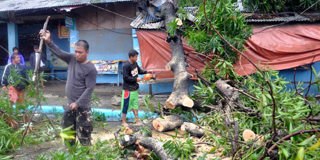 Workers clear the road off toppled trees after Typhoon Yutu slammed Isabela province in northeastern Philippines Tuesday, Oct. 30, 2018. A strong typhoon battered the northern Philippines on Tuesday, though officials were hopeful that successful evacuations would help avoid a repeat of the death and destruction wrought by a powerful storm last month. (AP Photo)