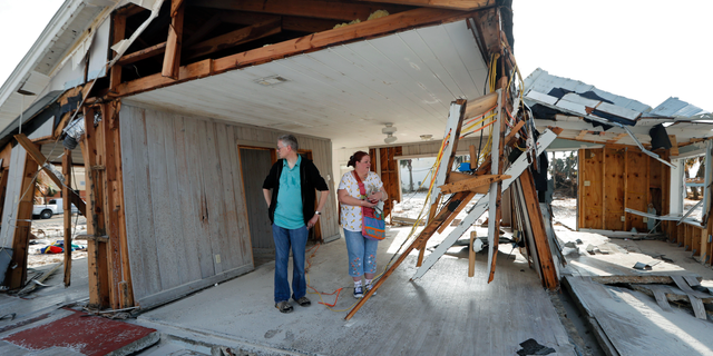 FILE - In this Oct. 17, 2018 file photo, Lanie Eden and her husband Ron stand in the destroyed vacation home they rented every year as they look for their possessions in the aftermath of Hurricane Michael in Mexico Beach, Fla. The tropical weather that turned into monster Hurricane Michael began as a relatively humble storm before rapidly blossoming into the most powerful cyclone ever to hit the Florida Panhandle, causing wrenching scenes of widespread destruction. (AP Photo/Gerald Herbert, File)