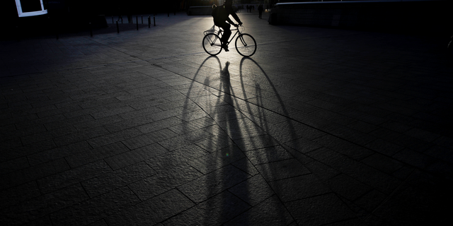 A man rides a bike in the early morning at the Porta Nuova business center in Milan, Italy, Wednesday, Oct. 24, 2018. (AP Photo/Luca Bruno)
