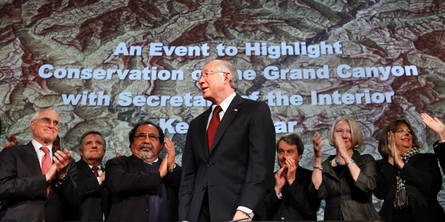 FILE - In this Jan. 9, 2012 file photo, then Interior Secretary Ken Salazar, center, standing in front of a map of the Grand Canyon, is applauded after announcing a twenty year ban on new mining claims near the Grand Canyon in Washington.  A federal appeals court has revived a challenge to a company's right to mine uranium near the Grand Canyon. The 9th U.S. Circuit Court of Appeals on Thursday, Oct. 25, 2018, said a lower court must determine whether the U.S. Forest Service erred in finding that Energy Fuels had a valid, existing right to mine outside the national park's South Rim entrance. Environmentalists and the Havasupai Tribe had challenged the Forest Service's decision. (AP Photo/Jacquelyn Martin, File)