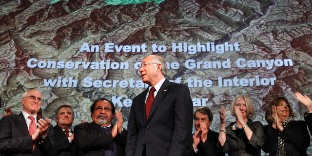 FILE - In this Jan. 9, 2012 file photo, then Interior Secretary Ken Salazar, center, standing in front of a map of the Grand Canyon, is applauded after announcing a twenty year ban on new mining claims near the Grand Canyon in Washington. A federal appeals court has revived a challenge to a company's right to mine uranium near the Grand Canyon. The 9th U.S. Circuit Court of Appeals on Thursday, Oct. 25, 2018, said a lower court must determine whether the U.S. Forest Service erred in finding that Energy Fuels had a valid, existing right to mine outside the national park's South Rim entrance. Environmentalists and the Havasupai Tribe had challenged the Forest Service's decision. (AP Photo/Jacquelyn Martin, File)