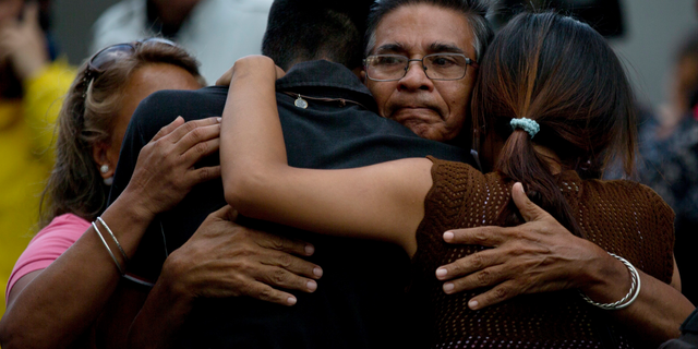 Staff members of jailed councilman Fernando Alberto Alban Salazar embrace outside the Bolivarian National Security Service (SEBIN) headquarters in Caracas, Venezuela, Monday, Oct. 8, 2018. Venezuela's Attorney General Tarek William Saab said Monday that Salazar, who was arrested on suspicion of involvement in a failed assassination attempt on President Nicolas Maduro, has died of suicide. (AP Photo/Fernando Llano)