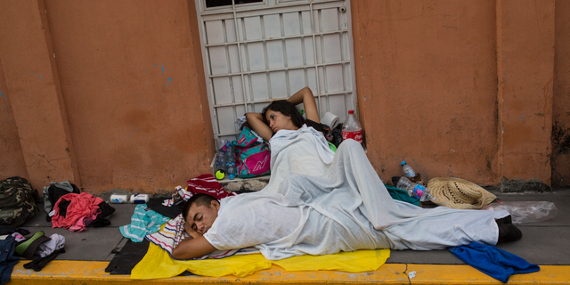 A migrant woman slowly begins to wake after sleeping on a sidewalk in Tapanatepec, Mexico, Sunday, Oct. 28, 2018. Thousands of migrants who are part of a caravan of Central Americans trying to reach the U.S. border took a break Sunday on their long journey toward the U.S. border.