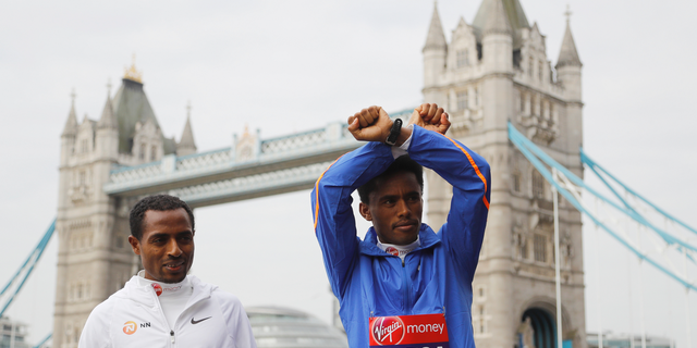 FILE - In this Thursday, April 20, 2017 file photo, Feyisa Lilesa, right, and Kenenisa Bekele from Ethiopia stand in front of the Tower Bridge in London. The Ethiopian marathon runner who made global headlines with an anti-government gesture at the Rio Olympics finish line has returned from exile, after sports officials assured him he will not face prosecution. Feyisa Lilesa's return from the United States on Sunday, Oct. 21, 2018 comes several months after a reformist new prime minister took office and announced sweeping reforms. (AP Photo/Frank Augstein, file)