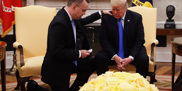 President Donald Trump prays with American pastor Andrew Brunson in the Oval Office of the White House, Saturday Oct. 13, 2018, in Washington.