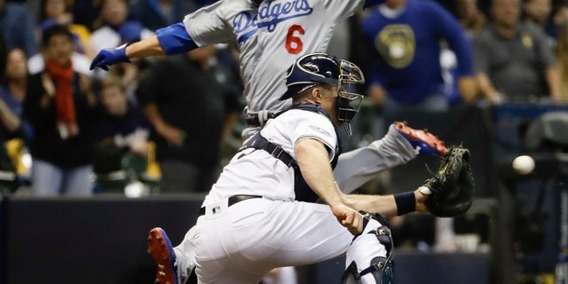 FILE - Los Angeles Dodgers' Brian Dozier scores past Milwaukee Brewers catcher Erik Kratz during the fifth inning of Game 6 of the National League Championship Series baseball game Friday.