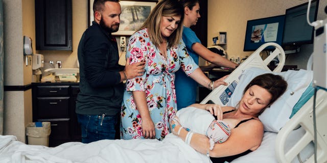 Rachel Checolinski, who was a surrogate for best friend Erin, holds baby Scottie shortly after giving birth.