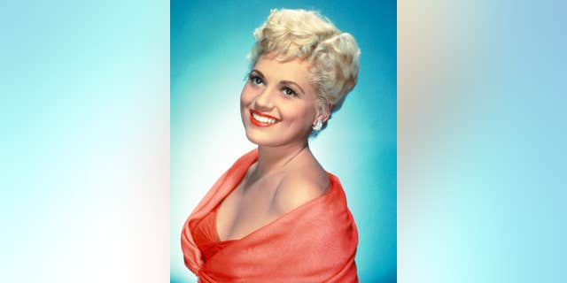 Judy Holliday (1921-1965) in a studio portrait, against a bluw background, circa 1950.